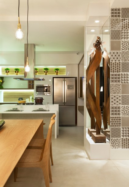 Cozinha Gourmet do Jovem Casal - Daniela Andrade. O mosaico em preto e branco surpreende o visitante de cara, enquanto outras paredes receberam acabamento em concreto aparente ou uma camada de vidro extraclean branco. A assinatura do designer Jader Almeida está presente na mesa Matriz com cinco cadeiras Bossa e nos pendentes Smith que se entrelaçam. Duas esculturas da artista Clores Lage e uma de Fernando Cardoso foram selecionadas para o espaço.
