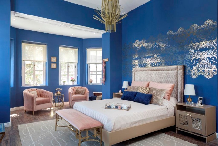 CASACOR Equador 2015. Índigo - Lorena Jervis e Maluli Loor (Magenta Arquitectura Interior). O quarto foi todo pintado de azul, com exceção do teto mantido na cor branca e do piso amadeirado. Os móveis guardam uma elegância clássica, com acabamentos em dourado - no melhor estilo Art Déco - e nos estofados em capitonê. Outro detalhe está nas filigranas em prata impressas na parede da cama, combinando com as portas dos aparadores laterais.
