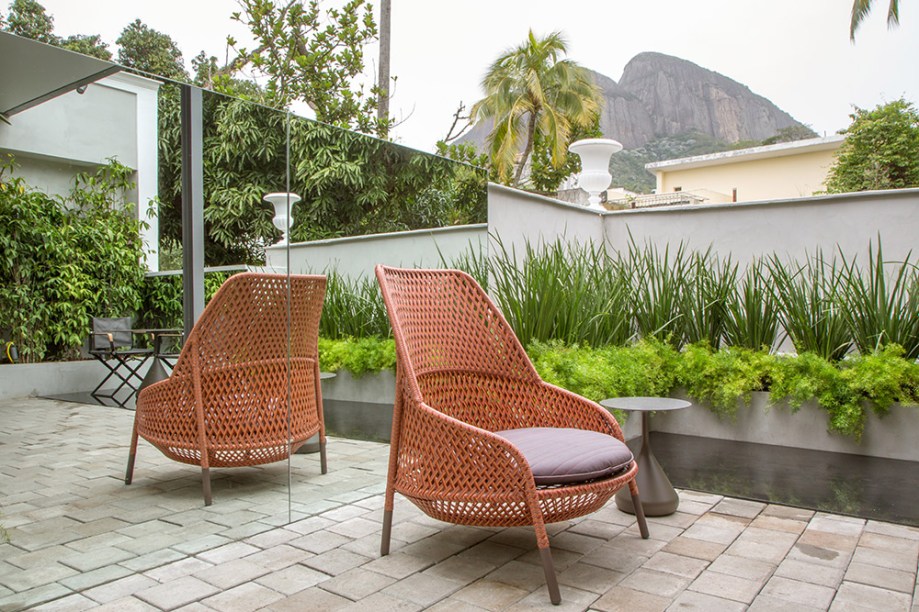 <span>Terraço do casal - Bruno Carvalho e Camila Avelar. Delicado e minimalista, o projeto convoca a escala monocromática de cinza. Ela valoriza tanto a natureza ao redor como contrasta com o colorido dos móveis da Dedon, by Collectania. Entre eles, mesas Satellite de Philippe Starck e a poltrona Mbrace Rocking Chair, de Sebastian Herkner.</span>