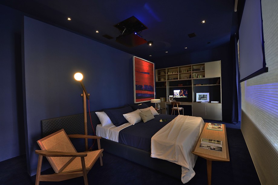 Loft For Life - Dany Bitencourt e Wagner Costa. A área íntima fica em um patamar elevado e traz móveis sob medida da Florense, incluindo os roupeiros com revestimento interno em couro matelassê. O azul profundo lava as paredes e o teto, conferindo profundidade e intimismo ao espaço.