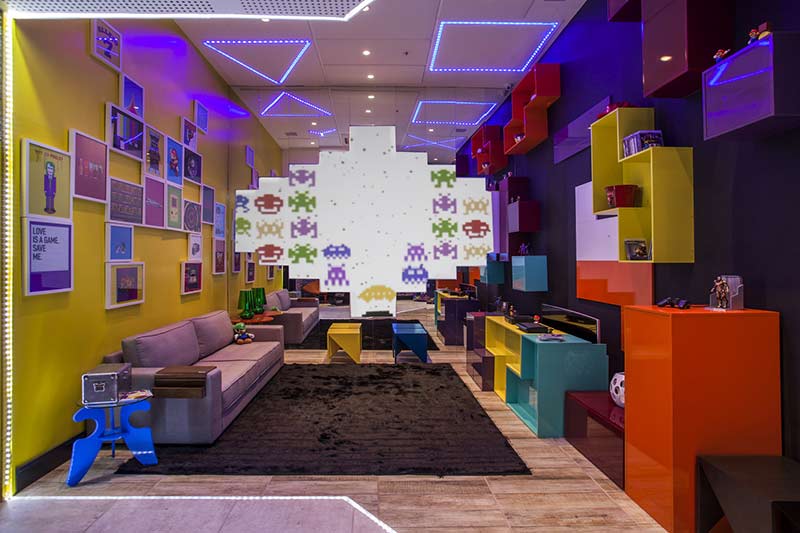 CASACOR Par&aacute; 2015: Game Room - Aniela Kalif e Pedro Ratis. O espa&ccedil;o simula uma viagem no tempo, que transporta o visitante para o universo cl&aacute;ssico de games. Dessa refer&ecirc;ncia geek vem a cartela de cores fortes, empregadas aqui com uma pegada retr&ocirc;. Geometrismos e volumetria s&atilde;o explorados com o aux&iacute;lio de marca&ccedil;&otilde;es feitas com LEDs.