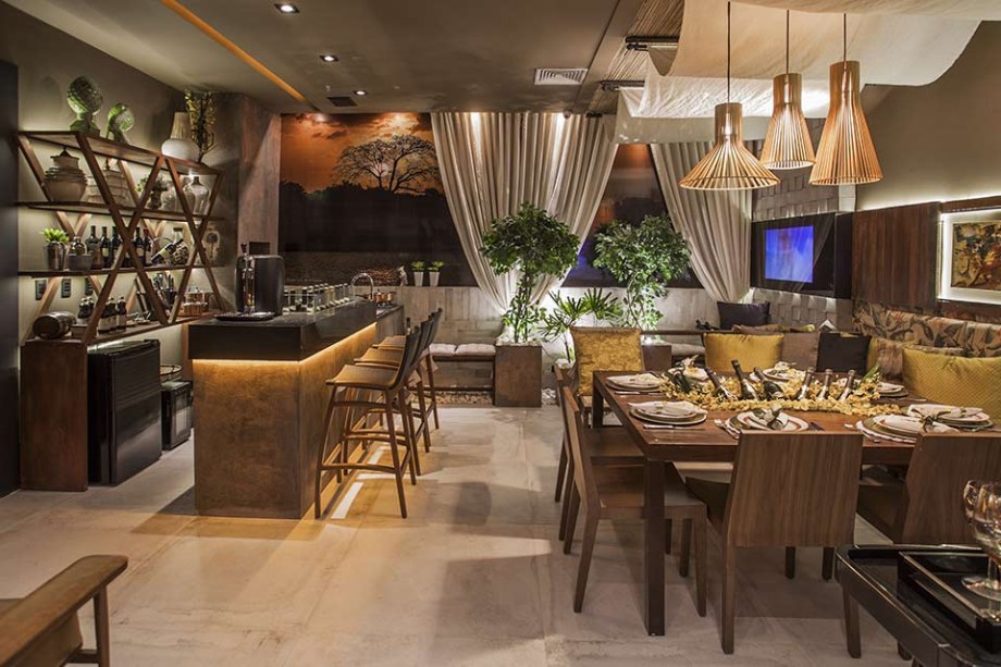 CASACOR Pará 2015. Varanda Lounge Bar - Lívia Santana. A paisagem da Baía do Guajara traz um clima especial para o espaço, que oferece um refúgio para reunir amigos e relaxar. O tom cinza e o calor da madeira definem a identidade do projeto, bem como os detalhes que remetem à cultura brasileira, a exemplo das estampas e do uso do crochê. Repare ainda na palha instalada no teto, acentuando a atmosfera acolhedora.