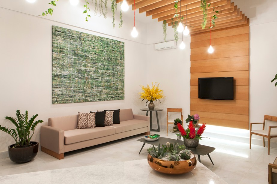 CASACOR Espírito Santo 2015. Sala de Espera - Liane Destefani. O branco é a cor mais associada à área de saúde, mas aqui é humanizado com a interferência bem-vinda da madeira e do verde, presente nas folhagens que preenchem a pérgola e na tela de arte.