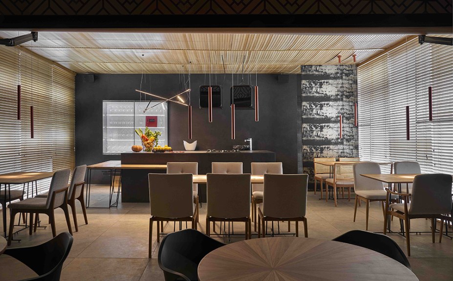 Restaurante - Du Leal e Eduardo Beggiato. Situada em um pavilhão fora do corpo da casa, a estrutura metálica forrada com tecido backlight cria uma caixa de luz. Nesta lona foram impressas formas ao estilo das grades usadas em Belo Horizonte na década de 1940. Outro efeito de luz e sombra vem das persianas em madeira, que preservam a vista da lagoa. Para se contrapor às paredes em porcenalato grafite fosco, foram adotadas mesas em madeira freijó clarinha e um piso em porcelanato com aparência de pedra.