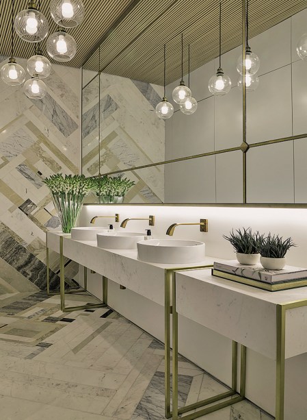CASACOR São Paulo 2016. Banheiro Feminino - Studio 011. As linhas art déco do edifício histórico do Jockey orientam o projeto de Barbara Gomes e Guiliana Savioli. O estilo também comanda o uso de detalhes dourados e espelhos no ambiente, onde predomina o off-white. No piso e na parede, destaque para o mosaico que aproveita mármores de diversas tonalidades. Já o teto ganha ripas de madeira em favor do aconchego.