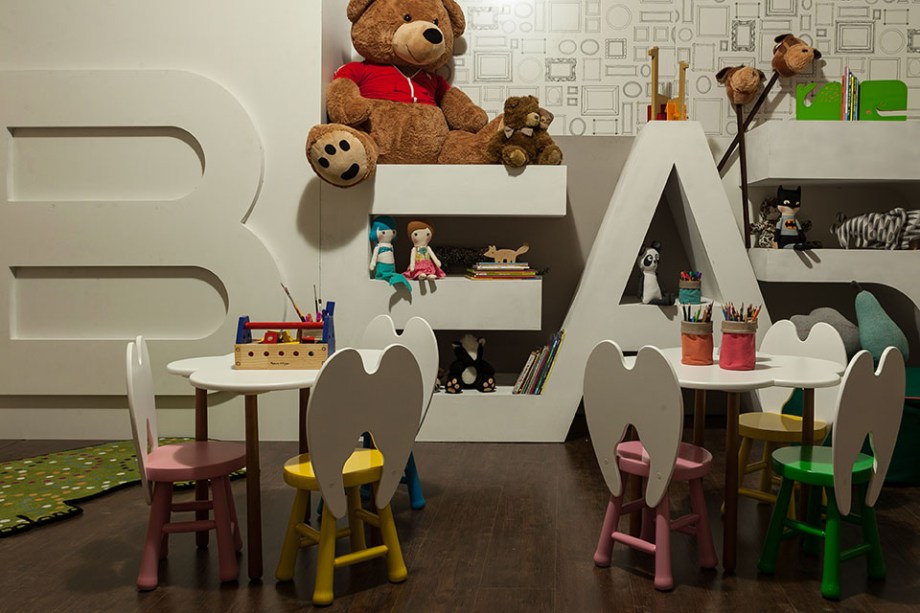 Espaço Kids - Cynthia Karas e Adelino Marinho Neto. Os arquitetos tinham em mente uma grande caixa de brinquedos ao projetar o espaço de 29,70m², onde todas as peças acompanham o tamanho dos pequenos na escala e na ergonomia. Uma grande árvore em MDF ocupa o ambiente, paginado com laminado vinílico escuro que reforça a atmosfera de floresta encantada. Paredes e forros foram revestidos em MDF frisado, sem acabamento, para dar a impressão de estar em uma caixa de brinquedos.