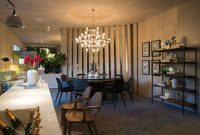Sala de Jantar da Família - André Monte. O design nacional é muito bem representado na seleção de peças, a começar pela estante e as cadeiras em madeira de Jader Almeida, que dialogam com o balcão em Ônix Provence. Também são de Jader as cadeiras que complementam a mesa de jantar de Victor Anguieira. O conjunto é regido pelo pendente Crown, da marca Nemo. Aliás, na iluminação André tirou partido da textura e deixou o teto livre, preferindo distribuir arandelas como a Foglio, da Flos, e a 204, da Arset, além do pendente de Ingo Maurer acima da bancada. A curadoria de arte ficou por conta de Aldonso Palacio Neto, com obras de artistas cearenses como Tulio Paracampos, Marco Ribeiro e Celso Oliveira.