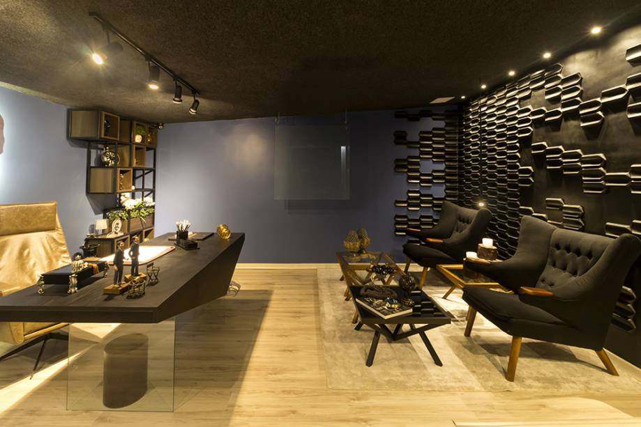CASACOR Paraíba 2016. Home Office do Publicitário – Carolina Hamad, Glenda Pontes e Rayssa Ferreira. O dia a dia de um colunista social inspirou a composição de apelo industrial, acentuado pelo uso da cor preta, pela estante em aço corten e o revestimento 3D na parede. O amadeirado claro no piso e a base em vidro na mesa de trabalho garantem a leveza. 