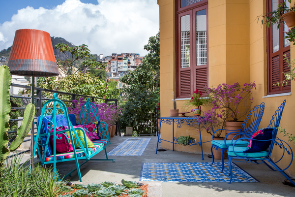 Jardim da Frida Kahlo - Paula Bergamin. Para deixar o ambiente mais alegre, Paula optou por tons fortes de azul, amarelo, rosa e turquesa. Itens de antiquário e outros contemporâneos contracenam com elementos usados e reciclados, como móveis de ferro, objetos antigos e tecidos garimpados no México. Repare também no piso pintado.