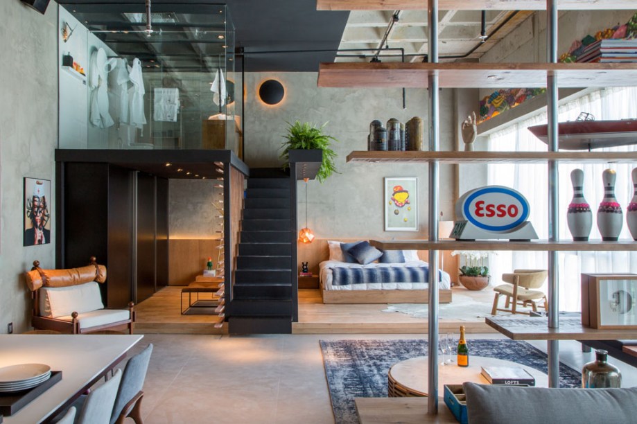 Loft do Solteiro - Alexandre Gedeon e Hugo Schwartz removeram o rebaixo de gesso existente para deixar aparente a estrutura da laje de concreto, além de tirar proveito do pé direito de quase 6m. Assim, o mezanino em aço passa a abrigar o banheiro. No nível inferior, ambientes público e privado são diferenciados pelo piso: frio para a área social (cozinha, estar e home theater) e de madeira no quarto e no closet. O conforto e o design estão aliados na poltrona Tonico, de Sérgio Rodrigues, e na cadeira Joy, de Jader de Almeida. As mesas Fafá G e Fafá M são de Rejane Carvalho. Em primeiro plano, a estante que divide estar e home theater, criação da dupla, é toda feita com tábuas de pinho e estrutura tipo andaime em ferro.