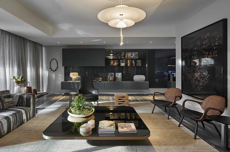Mobiliário de design brasileiro e italiano aquecem a sala <span>recoberta com o mármore Petra Minas: duas poltronas Clad de Jader Almeida à direita, ao fundo a poltrona da linha BK22 da Casual e o banco Wiggle Stool do designer Frank Gehry, feito de papelão ondulado para a Vitra. CASACOR Minas Gerais 2016. Sala Central - Patrícia Hermanny.</span>