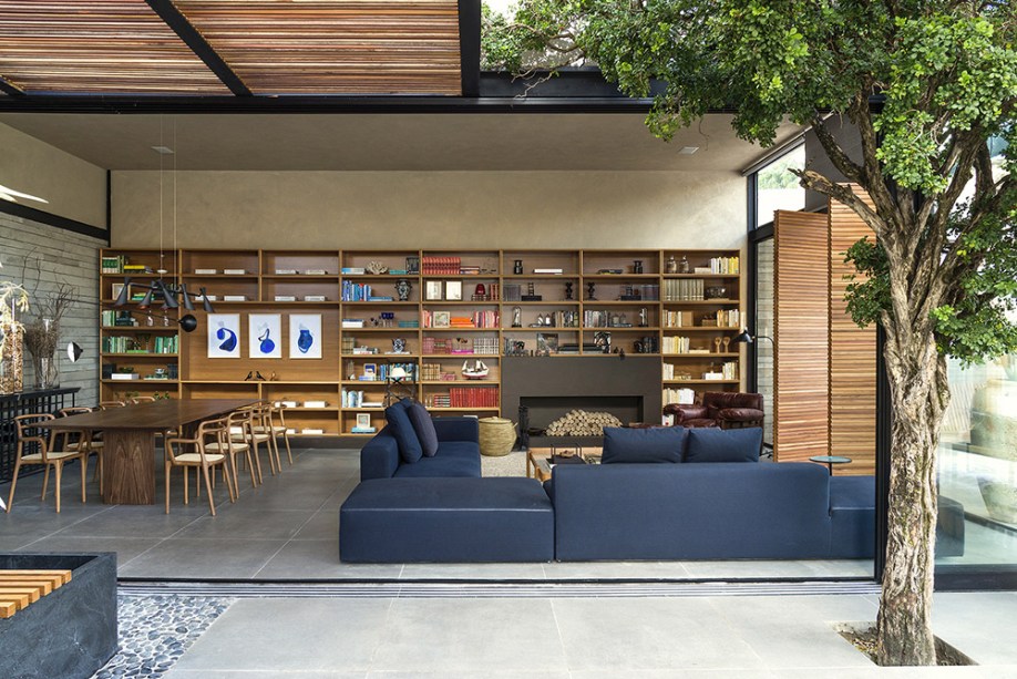 CASACOR Goiás 2017. Nando Nunes - Refúgio da Pérgola. A estante na cor louro freijó corresponde à dimensão do espaço, na mesma escala generosa do sofá Herman, dos designers Danilo Lopes e Paula Gontijo. Do lado oposto, vem a mesa de jantar com cadeiras de Andrea Borgoni, lançamento no Salão de Milão. Acima, pendente articulado Zig Zag.