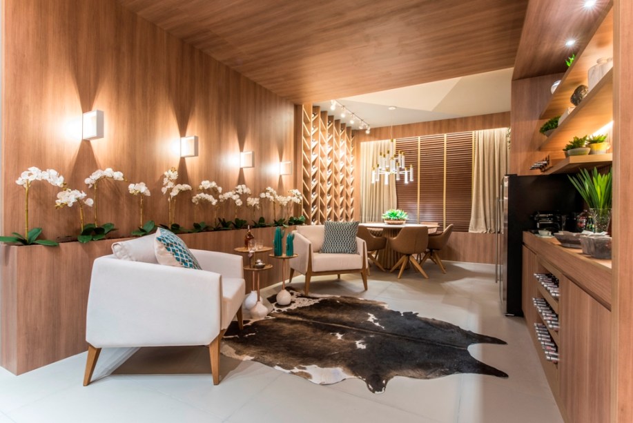 Adega Chivas - Débora Farias. Para um casal apreciador de bebidas, um ambiente acolhedor e relaxante, com iluminação indireta e a madeira em destaque, delimitando visualmente um pórtico. As garrafas foram destacadas na estante de autoria da profissional, com inspiração na padronagem chevron - uma das tendências da mostra.