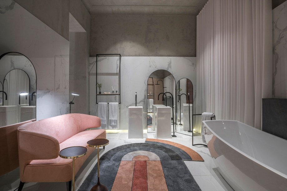 <span>Rodrigo Aguiar traz para a mostra mineira uma <strong>Sala de Banho</strong> nobre e sofisticada, com uma paleta de cor neutra. Para dar vida e cor ao espaço, o profissional insere um sofá curvo rosa, da loja Micheliny Martins, ultraconfortável que conversa com o desenho retrô do tapete.</span>