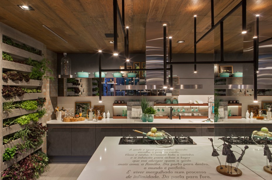 Cozinha Ninho - Luís Alfredo Marques e Luciana Rogério. O projeto prevê a cozinha como espaço de convívio social com conforto e praticidade. Uma horta com manjericão, alecrim, hortelã, salsinha, cebolinha alface e rúcula deixam temperos e hortaliças frescos e ao alcance das mãos na hora de cozinhar. Materiais atemporais, como o concreto e tijolo à mostra, unem-se à modernidade das peças que compõem o mobiliário.