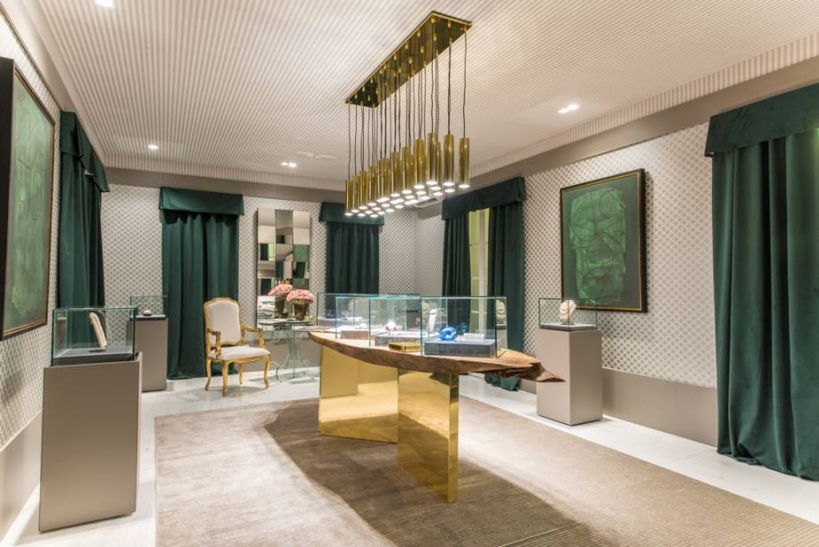 CASACOR RN: Espaço Esmeralda - Leonardo Augusto, Lígia Martins e Marianna Procópio. Cortinas em veludo no tom Greenery e o dourado se impõem. A mesa promove o contraste entre luxo e rusticidade, com seu tampo de madeira de demolição centenária. O cinza é escolhido como pano de fundo, em favor de uma atmosfera contemporânea.