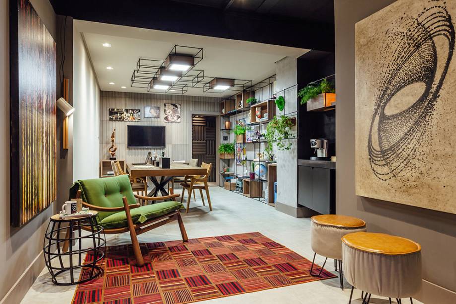 CASACOR Rio Grande do Sul. <span>Studio de Design - Márcio Moreira, Magali Montani e Ana Paula Weber. O espírito é colaborativo, afirmado na grande mesa de trabalho e reuniões. O estilo mescla o escandinavo e o industrial em peças como a estante móvel, com estrutura de metal e caixas de madeira. A linguagem é replicada na iluminação. Ao fundo, o revestimento da Linha Cinética (Solarium) tem inspiração em brises, sugerindo movimento conforme a incidência de luz.</span>