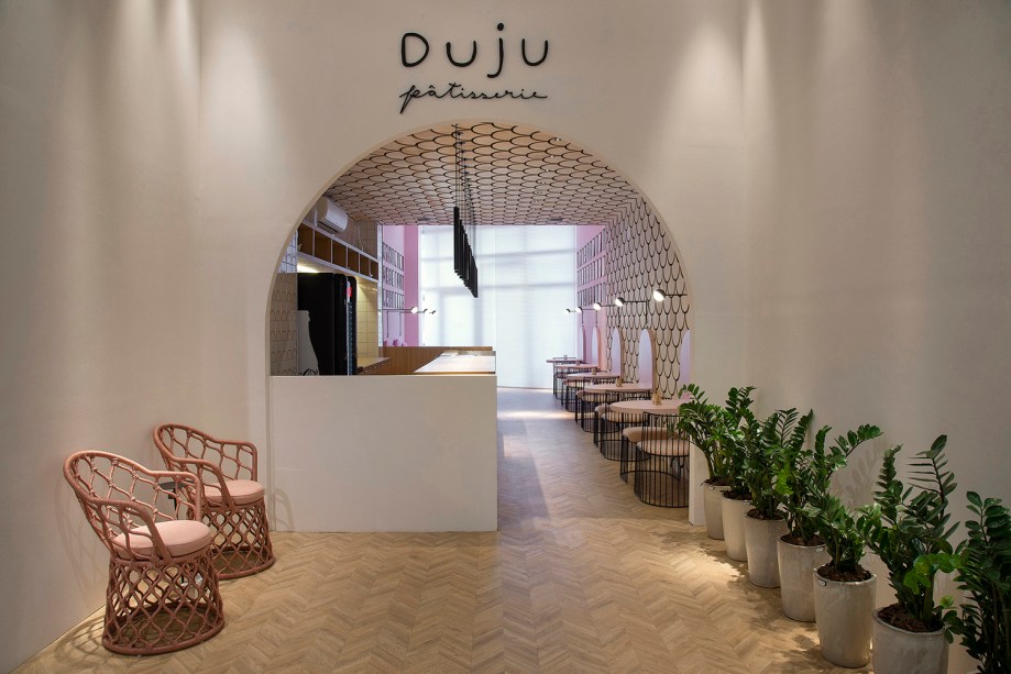 Duju Pâtisserie – Eduardo Medeiros. Neste ambiente de tons pastéis, vários elementos arquitetônicos remetem ao U da logomarca. Ele é citado no acesso em formato de arco, nas mesinhas laterais e até no revestimento em madeira que percorre paredes e o teto. Em primeiro plano, poltronas Painho, da Tidelli.