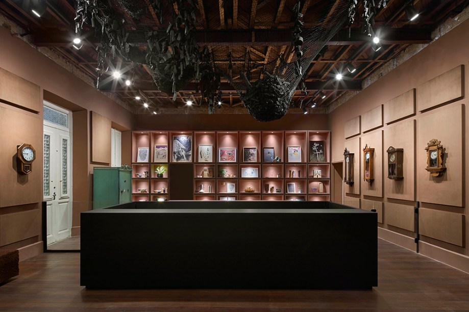 Bilheteria + Loja - Alexandre Rousset e Ana Vaz. O espaço reverencia o acervo histórico e as memórias do Casarão. Protagonista absoluta, a galeria de relógios se revela, guardados em nobres caixas de madeira. Ana Vaz teceu à mão, em palha de seda pura, a trama que sustenta quilos e quilos de carvão, flutuando no espaço.