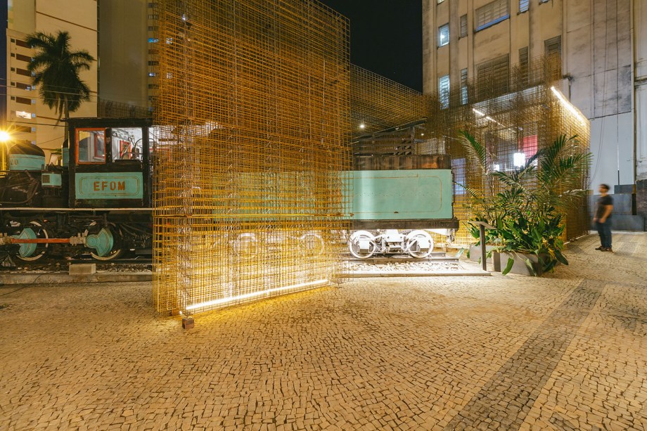 Pavilhão Nuvem - Arquitetos Associados. A partir de um módulo de paredes em telas soldadas de vergalhão, surge a estrutura efêmera, pensada mais como sistema e menos como objeto. Essa nuvem de aço, que pode ser remontada em outros contextos, abriga e revela sutilmente o interior, enquanto desenha um lugar de pausa para o visitante.