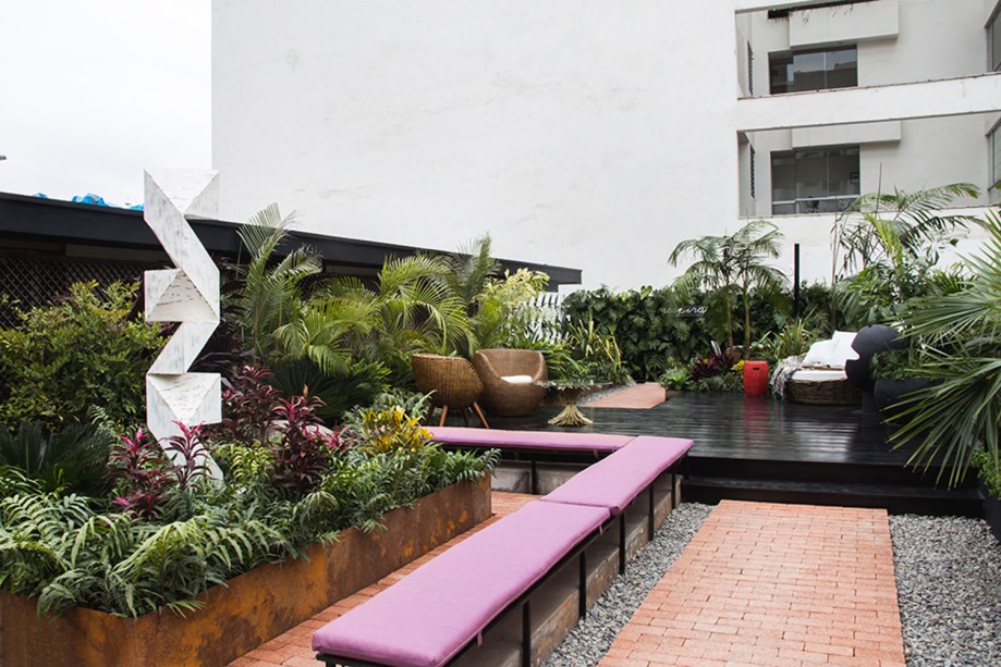 Rooftop - Raúl Arróspide. Em Lima, há muitos telhados planos e transitáveis, onde é possível criar espaços alternativos próximos da natureza. O deck convida a contemplar o jardim, repleto de espécies tropicais e contornado pelos futons na cor rosa. A escultura, em sintonia com o paisagismo, é do artista peruano Aldo Chaparro.