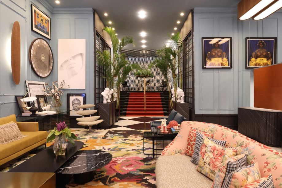 CASACOR São Paulo 2019. Lisandro Piloni - Foyeur Bienvenue. Arte por todos os lados sobre boiserie clássica. O balcão de atendimento, à direita na foto, ganhou um revestimento em madeira que tem a aparência do mármore Nero Marquina. O canapé de antiquário foi repaginado com tecidos estampados e é original da década de 1940, no estilo Hollywood Regency. A mesa, no alto, é uma peça italiana em metal dourado com conchas nacaradas e base em madeira laqueada. Acima, kokedamas suspensas com cabos de aço.