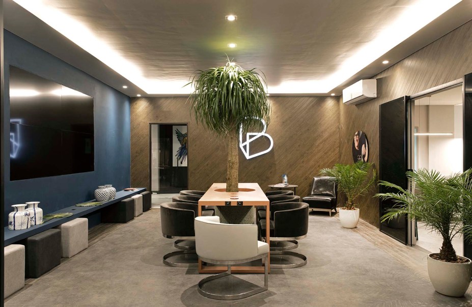 Lounge Banestes - Sergio Paulo Rabello. Há várias experiências tecnológicas oferecidas neste ambiente de 42 m², como o carregamento de celular por indução magnética na bancada central. Os tons de marinho e madeira remetem à identidade visual do banco que dá nome ao espaço, enquanto o paisagismo humaniza e reforça a noção de sustentabilidade.