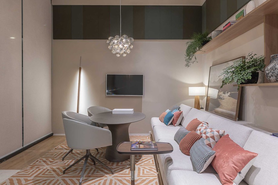 A sala multifuncional assinada por Athié Wohnrath destaca um grande sofá planejado que orienta o layout. Diferentes tonalidades de azul garantem uma descontração ao ponto de encontro, reforçada pelo tapete geométrico coral e pela composição não simétrica das prateleiras.