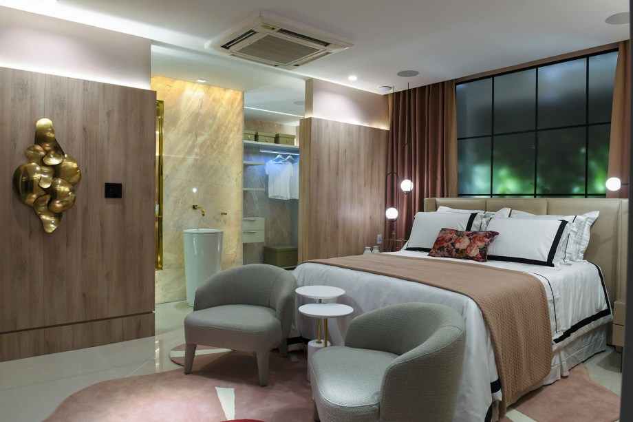 Suíte Gloss - Mila Caramelo e Mila Saraiva. A suíte 'e inspirada em uma “it girl” romântica e conectada. O ambiente integra mobiliário de design, muro verde, sustentabilidade e automação. A paleta de cores delicadas, de beges e rosas, Conte com o toque glamuroso do dourado com preto e terracota. O generoso closet, penteadeira megaequipada e mini estar para receber as amigas, fazem da Suíte Gloss objeto de desejo para mulheres.