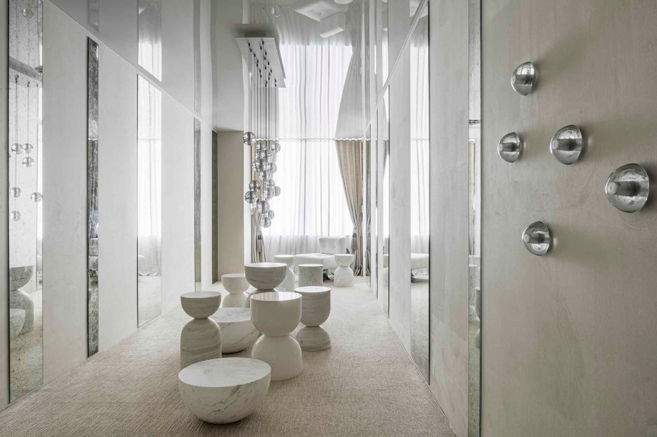 CASACOR Miami 2019. Objects - Light on White. Imaginado como uma caixa de jóias com móveis preciosos, este espaço apresenta silhuetas marcantes esculpidas em um único bloco de mármore ou madeira com acabamento em laca brilhante. À medida que a coleção de mesas dança em uma iluminação divertida projetada por Omer Arbel, os espelhos convidam os espectadores a descobrir a poesia visual de diferentes ângulos.
