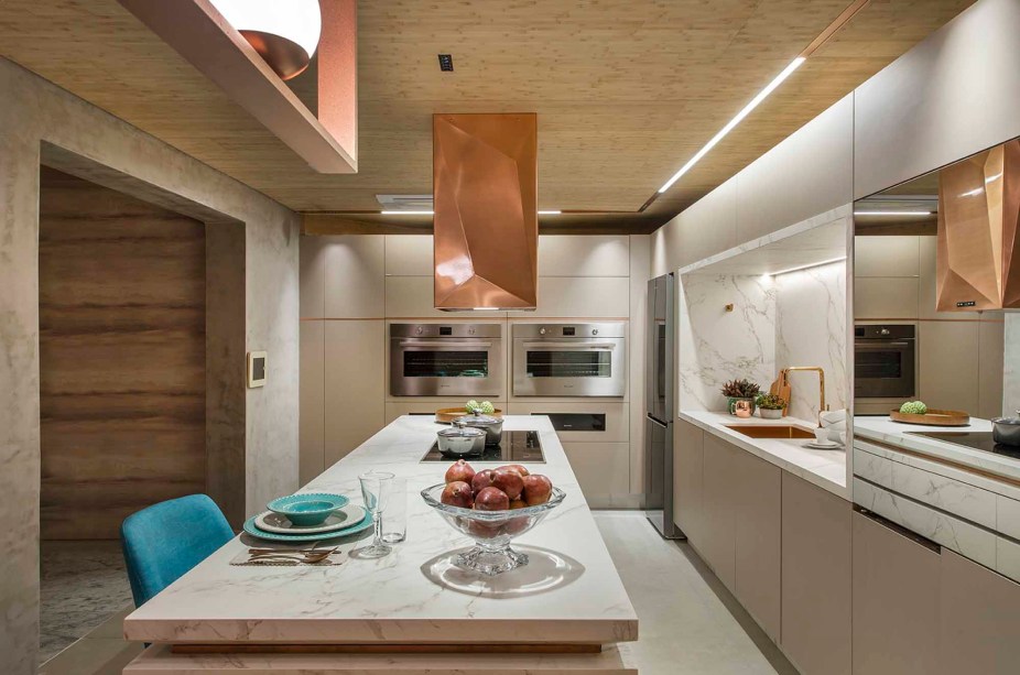 CASACOR Ribeirão Preto 2019. Luana Milani e Ricardo Pagnano - Cozinha de Todos. Teto em bambu e peças de cobre convivem e somam as sensações de acolhimento e sofisticação - dois conceitos essenciais do projeto. Repare que o cobre aparece no lustre, nos filetes que contornam a bancada e na coifa com desenho exclusivo. O contraste vem do Dekton, na cor Entzo Natural, aplicado na pia, na bancada e na frente das gavetas.