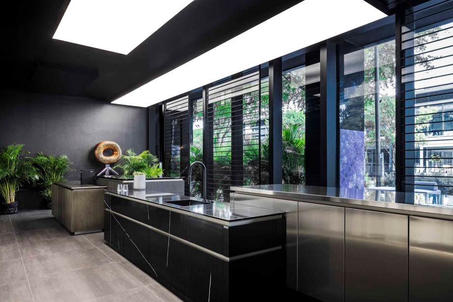Ydzn Bar - Yodezeen. O design do Ydzn Bar baseia-se na conexão das esferas contrastantes da vida: cozinhar, relaxar, comunicar e até trabalhar. Cores escuras com toques de materiais naturais, como pedra e madeira, conectam-se com caixas de luz e um jardim vertical que transforma a barra em um local exclusivo. Uma TV grande na frente da sala reconhece o entretenimento como uma atividade social inerente. Uma bancada elegante de pedra natural proporciona sensações táteis agradáveis, enquanto móveis contemporâneos feitos sob medida formam a parte principal da sala. Eles focam a atenção na ideia principal: funcionalidade e soluções para design centradas no homem.