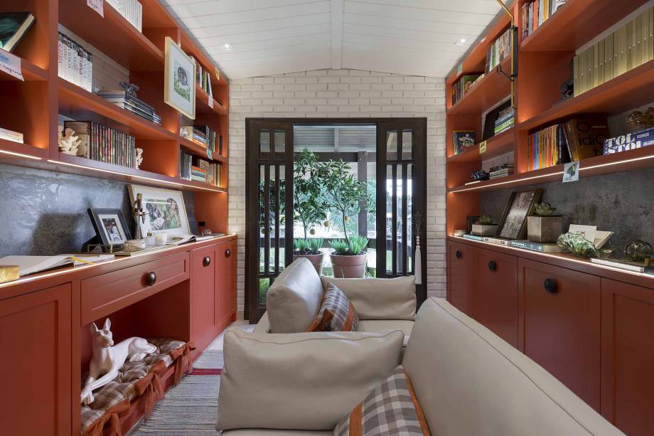 Da mesma forma, a arquitetura sensorial é obtida através das cores na biblioteca Books‘N Art, de Gabriela Herde. Em um tom vermelho cheio de energia, os livros ficam emoldurados com estilo. A marcenaria planejada organiza e expõe todos os elementos. Books‘N Art - Gabriela Herde - CASACOR Balneário Camboriú 2019.