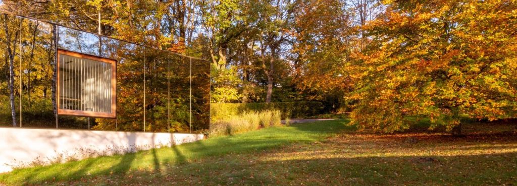 Fachada espelhada refletindo bosque com folhas de outono
