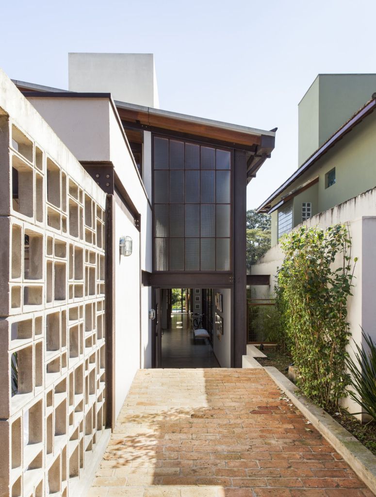 fachada da casa com revestimento em vidro e teto inclinado