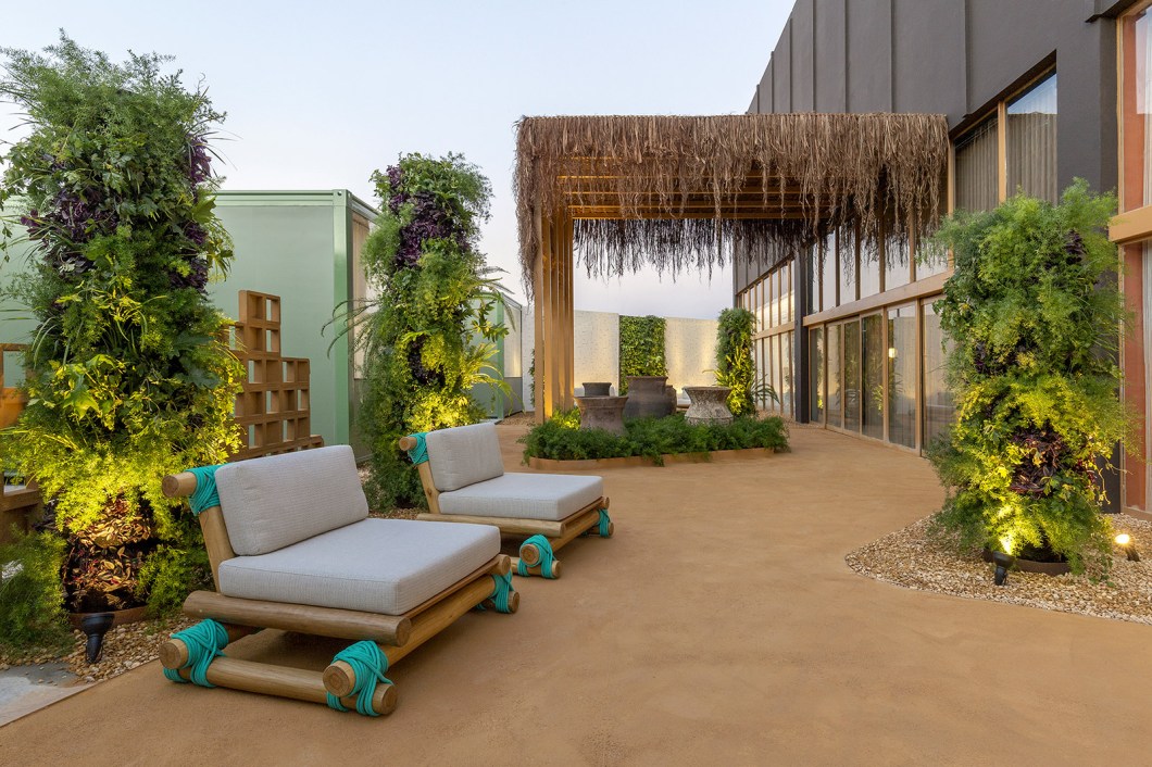 Flávia Araújo e Ricardo Lima - Jardim Woo. Em tupi-guarani, "woo" significa "o lugar das emoções". E é a partir dessa premissa que a dupla de profissionais utiliza a arquitetura vernacular indígena brasileira como a inspiração para se reconectar com a ancestralidade, com as raízes e com a terra. O espaço cênico cria uma floresta onde totens de jardins verticais representam as árvores, a piaçava do pergolado remete a uma oca e a desconstrução dos passeios sugere a imperfeição das trilhas abertas na mata. Flávia Araújo e Ricardo Lima - Jardim Woo. Em tupi-guarani, "woo" significa "o lugar das emoções". E é a partir dessa premissa que a dupla de profissionais utiliza a arquitetura vernacular indígena brasileira como a inspiração para se reconectar com a ancestralidade, com as raízes e com a terra. O espaço cênico cria uma floresta onde totens de jardins verticais representam as árvores, a piaçava do pergolado remete a uma oca e a desconstrução dos passeios sugere a imperfeição das trilhas abertas na mata.