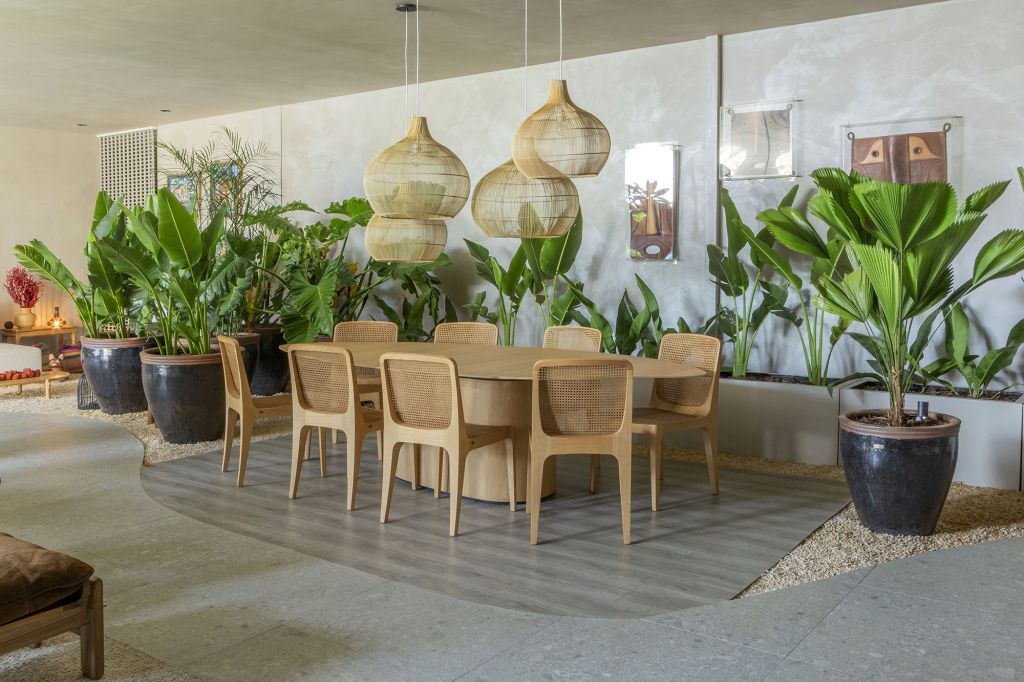 Lounge Garden, projeto de Pedro Ernesto e Leandra Castro para a CASACOR Goiás 2021. Na foto, sala de jantar e jantare, com móveis de madeira, vasos de plantas e quadros.