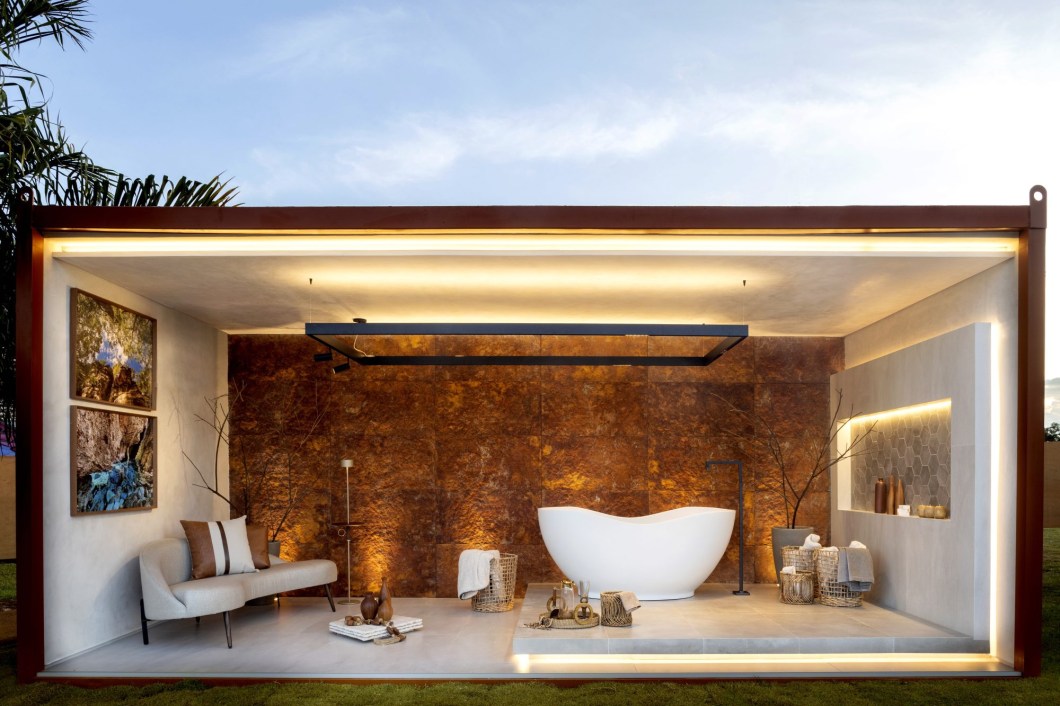 Deyse Cristina Arquitetura - Bálsamo do Cerrado. O ponto inspiração do ambiente é a parede ao fundo, com um revestimento que remete a um forte elemento do Tocantins, a terra vermelha. Pensada pra ser um ambiente de cura e prazer, a Sala de Banho Bálsamo do Cerrado conta com um Estar e Banho integrados. O mobiliário escolhido traz a sobriedade dos tons neutros, variando do bege ao cinza. Uma iluminação indireta de cor quente foi escolhida para proporcionar ainda mais momentos de tranquilidade. Deyse Cristina Arquitetura - Bálsamo do Cerrado. O ponto inspiração do ambiente é a parede ao fundo, com um revestimento que remete a um forte elemento do Tocantins, a terra vermelha. Pensada pra ser um ambiente de cura e prazer, a Sala de Banho Bálsamo do Cerrado conta com um Estar e Banho integrados. O mobiliário escolhido traz a sobriedade dos tons neutros, variando do bege ao cinza. Uma iluminação indireta de cor quente foi escolhida para proporcionar ainda mais momentos de tranquilidade.