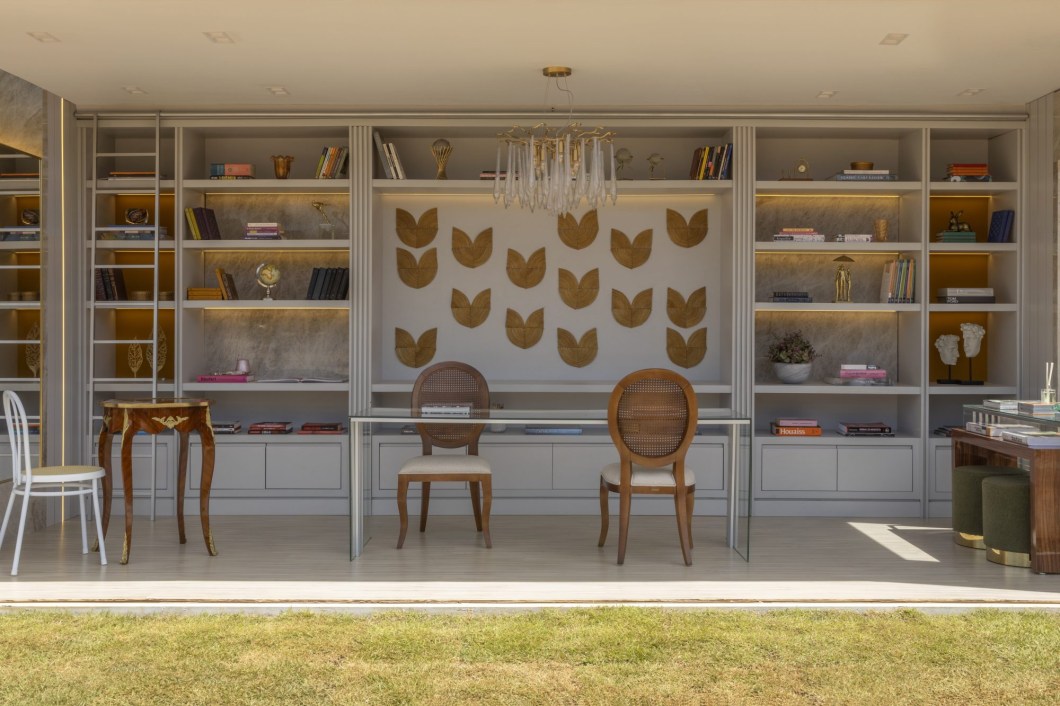 Freires Antunes Arquitetura- Livraria. O uso de artesanato regional foi a inspiração das arquitetas Brenda Freire e Géssica Antunes para o ambiente. O intuito foi resgatar os novos hábitos de leitura neste momento pós pandemia! O Capim Dourado, espécie encontrada em diversas regiões do cerrado brasileiro, inclusive no Jalapão, ganhou destaque no projeto. Utilizado como elemento decorativo e feito por uma artesã tocantinense, o mosaico na estante clássica cria uma atmosfera delicada e ponto de luz representando o sol, elemento marcante na paisagem regional. As paletas de cores cinza e mostarda geram contraste à iluminação de design e acabamento dourado, remetendo aos elementos da natureza. Freires Antunes Arquitetura- Livraria. O uso de artesanato regional foi a inspiração das arquitetas Brenda Freire e Géssica Antunes para o ambiente. O intuito foi resgatar os novos hábitos de leitura neste momento pós pandemia! O Capim Dourado, espécie encontrada em diversas regiões do cerrado brasileiro, inclusive no Jalapão, ganhou destaque no projeto. Utilizado como elemento decorativo e feito por uma artesã tocantinense, o mosaico na estante clássica cria uma atmosfera delicada e ponto de luz representando o sol, elemento marcante na paisagem regional. As paletas de cores cinza e mostarda geram contraste à iluminação de design e acabamento dourado, remetendo aos elementos da natureza.