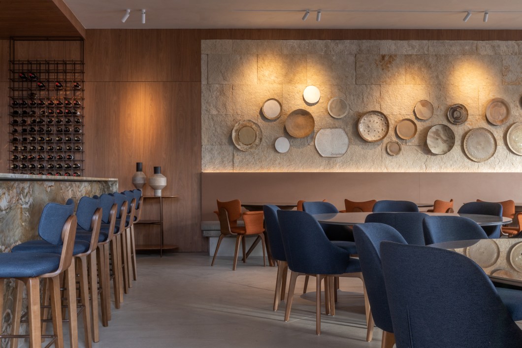 Tatiana Guedes - Restaurante Bar. Um dos lugares que promete reunir visitantes, o local operado pelo Marie Cuisine aposta nas memórias afetivas longevas das porcelanas penduradas nas paredes, com pratos cerâmicos exclusivamente moldados para o ambiente. Entre os elementos utilizados, painéis de mdf jatobá brasileiro, mobília de nogueira, vidro e pedra natural, textura de palha e couro nas cadeiras e linho nas cortinas. No bar, destaca-se o balcão iluminado de quartzito crystal fusion. O verde e o azul integram o local em momentos únicos, com uma vista espetacular do pôr do sol na praça arborizada da mostra. Tatiana Guedes - Restaurante Bar. Um dos lugares que promete reunir visitantes, o local operado pelo Marie Cuisine aposta nas memórias afetivas longevas das porcelanas penduradas nas paredes, com pratos cerâmicos exclusivamente moldados para o ambiente. Entre os elementos utilizados, painéis de mdf jatobá brasileiro, mobília de nogueira, vidro e pedra natural, textura de palha e couro nas cadeiras e linho nas cortinas. No bar, destaca-se o balcão iluminado de quartzito crystal fusion. O verde e o azul integram o local em momentos únicos, com uma vista espetacular do pôr do sol na praça arborizada da mostra.
