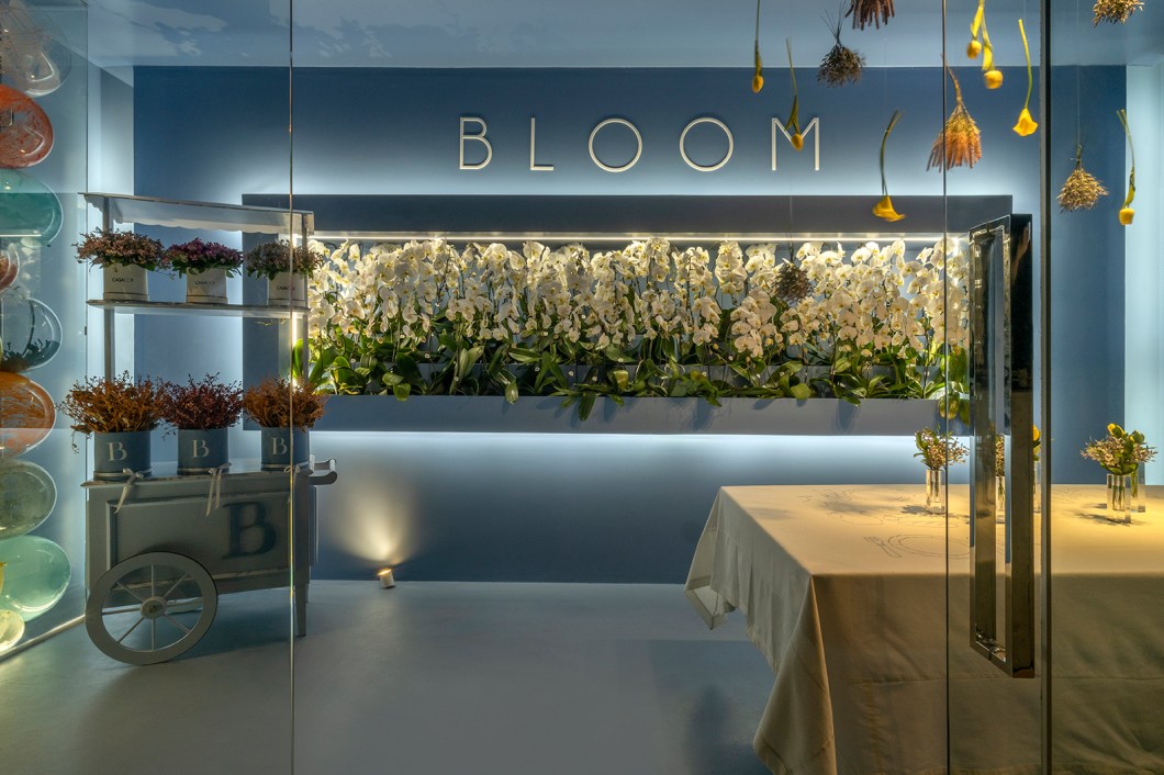 Roberto Guedes - Bloom. Um dos ambientes mais instagramáveis da mostra, Roberto Guedes projetou uma parede de balões e flores excêntricas. Iluminação de led dá o charme ao ambiente minimalista. A inspiração do arquiteto foi em lojas italianas ligadas à área de moda e flores, após uma longa pesquisa na forma como estabelecimentos desses nichos apresentam suas criações. Com 18 m² em construção modular, o ambiente utiliza a cor azul tibet. Usando a mesma cor em todo o ambiente com o intuito de levar o visitante a valorizar apenas um momento, o espaço traz ornamentação com pratos exclusivos, vasos e flores. Roberto Guedes - Bloom. Um dos ambientes mais instagramáveis da mostra, Roberto Guedes projetou uma parede de balões e flores excêntricas. Iluminação de led dá o charme ao ambiente minimalista. A inspiração do arquiteto foi em lojas italianas ligadas à área de moda e flores, após uma longa pesquisa na forma como estabelecimentos desses nichos apresentam suas criações. Com 18 m² em construção modular, o ambiente utiliza a cor azul tibet. Usando a mesma cor em todo o ambiente com o intuito de levar o visitante a valorizar apenas um momento, o espaço traz ornamentação com pratos exclusivos, vasos e flores.