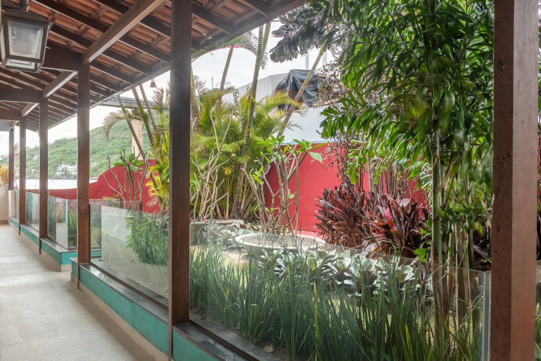 Sérgio Paulo Rabello - Jardim das Suítes. O Jardim das Suítes foi projetado pelo arquiteto Sérgio Paulo Rabello para ser um lugar realmente aprazível. Assim que as portas dos quartos são abertas, revela-se um lugar feliz, agradável de se ver, bem junto ao mar. No local, já existiam palmeiras e arbustos de grande porte que foram preservados. A vegetação acrescentada tem tons de vinho, acompanhando aquela já existente. Completamos as palmeiras junto ao muro para formatar um lindo maciço de plantas. No meio do jardim de 30 m² foram colocados discos com jasmim-manga (Plumeria rubra) uma árvore nativa da América Tropical, cujos caules formam esculturas. Esse formato escultural da espécie faz com que o jardim se torne ainda mais design, ideal para um evento que se chama CASACOR. À noite, a iluminação direcionada às espécies garante um ar cênico ao espaço. Sérgio Paulo Rabello - Jardim das Suítes. O Jardim das Suítes foi projetado pelo arquiteto Sérgio Paulo Rabello para ser um lugar realmente aprazível. Assim que as portas dos quartos são abertas, revela-se um lugar feliz, agradável de se ver, bem junto ao mar. No local, já existiam palmeiras e arbustos de grande porte que foram preservados. A vegetação acrescentada tem tons de vinho, acompanhando aquela já existente. Completamos as palmeiras junto ao muro para formatar um lindo maciço de plantas. No meio do jardim de 30 m² foram colocados discos com jasmim-manga (Plumeria rubra) uma árvore nativa da América Tropical, cujos caules formam esculturas. Esse formato escultural da espécie faz com que o jardim se torne ainda mais design, ideal para um evento que se chama CASACOR. À noite, a iluminação direcionada às espécies garante um ar cênico ao espaço.