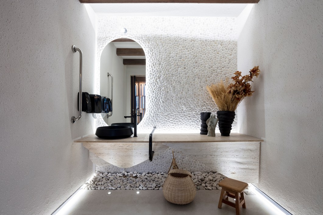 Isabela Dourado e Luciana Dourado - Espaço Caraíbas. O banheiro acessível assinado pelo escritório Inova Arquitetura é inspirado no estilo wabi-sabi e traz um refúgio que celebra a perfeição do imperfeito e a sua aceitação. Os elementos naturais, como barro, pedras e parede de taipa, remetem à história e à identidade regional da região de Irecê. É um ambiente funcional e acolhedor, que valoriza a essência da cultura local. Isabela Dourado e Luciana Dourado - Espaço Caraíbas. O banheiro acessível assinado pelo escritório Inova Arquitetura é inspirado no estilo wabi-sabi e traz um refúgio que celebra a perfeição do imperfeito e a sua aceitação. Os elementos naturais, como barro, pedras e parede de taipa, remetem à história e à identidade regional da região de Irecê. É um ambiente funcional e acolhedor, que valoriza a essência da cultura local.