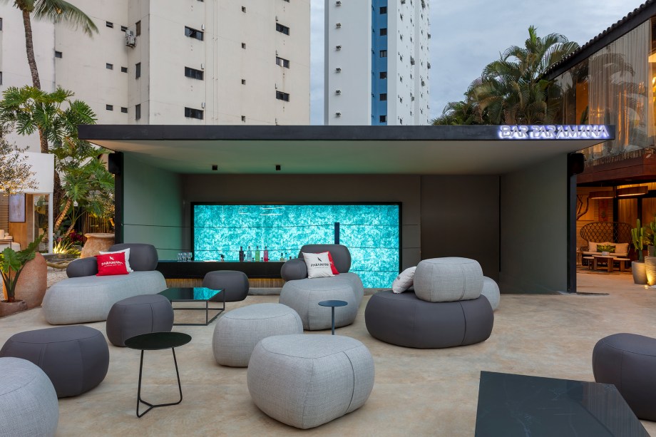 Lorena Damasio Arquitetura - The Bar. Ambiente projetado para ser o bar da edição de 2023. A estrutura foi construída dentro da piscina existente no imóvel original e, por conta disso, o elemento água foi utilizado como conceito do projeto. A fluidez da água é representada nos móveis orgânicos, que remetem a seixos. Além disso, pedras naturais também foram utilizadas no espaço para criar uma atmosfera leve e harmoniosa, reforçando a conexão com elementos naturais.
