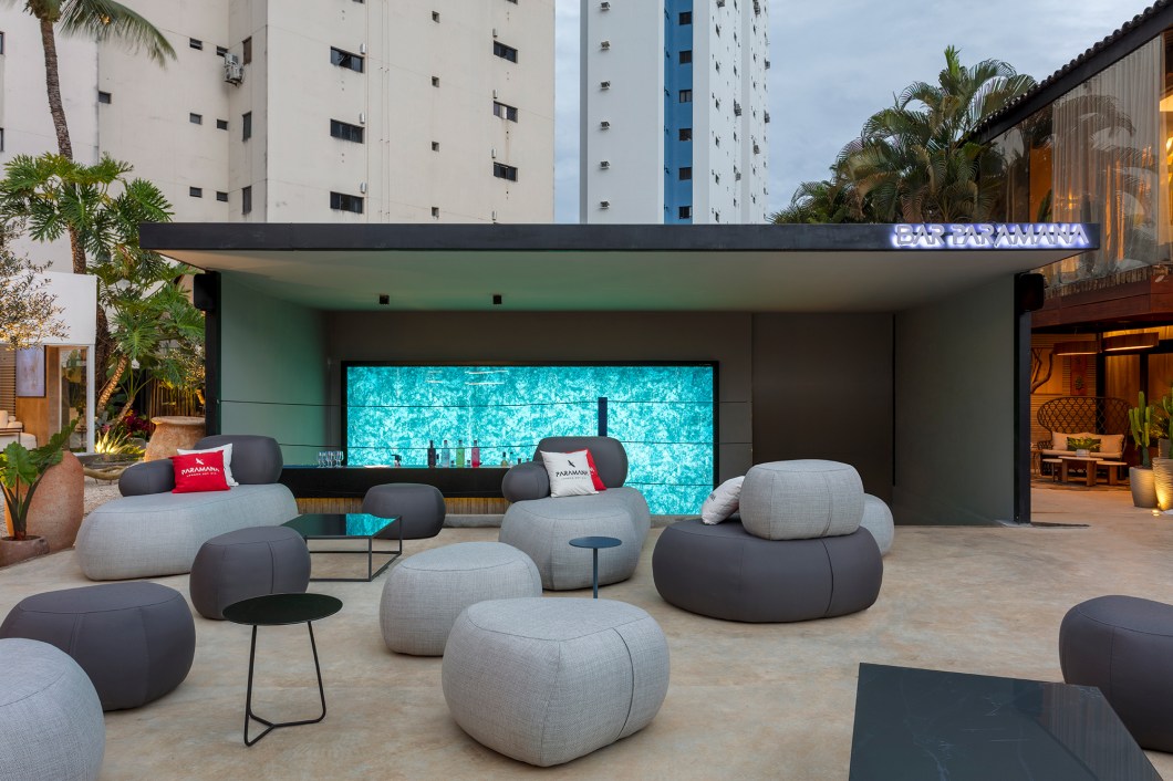 Lorena Damasio Arquitetura - The Bar. Ambiente projetado para ser o bar da edição de 2023. A estrutura foi construída dentro da piscina existente no imóvel original e, por conta disso, o elemento água foi utilizado como conceito do projeto. A fluidez da água é representada nos móveis orgânicos, que remetem a seixos. Além disso, pedras naturais também foram utilizadas no espaço para criar uma atmosfera leve e harmoniosa, reforçando a conexão com elementos naturais. Lorena Damasio Arquitetura - The Bar. Ambiente projetado para ser o bar da edição de 2023. A estrutura foi construída dentro da piscina existente no imóvel original e, por conta disso, o elemento água foi utilizado como conceito do projeto. A fluidez da água é representada nos móveis orgânicos, que remetem a seixos. Além disso, pedras naturais também foram utilizadas no espaço para criar uma atmosfera leve e harmoniosa, reforçando a conexão com elementos naturais.