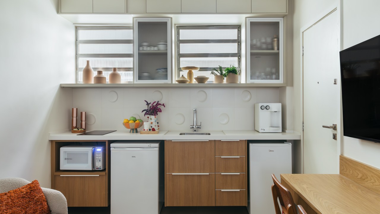 Loft de 30 m² é projetado para administradora de 80 anos que mora sozinha. Projeto de Richard de Mattos, da Casa Cururu. Na foto, cozinha com armários de madeira e tampo branco.