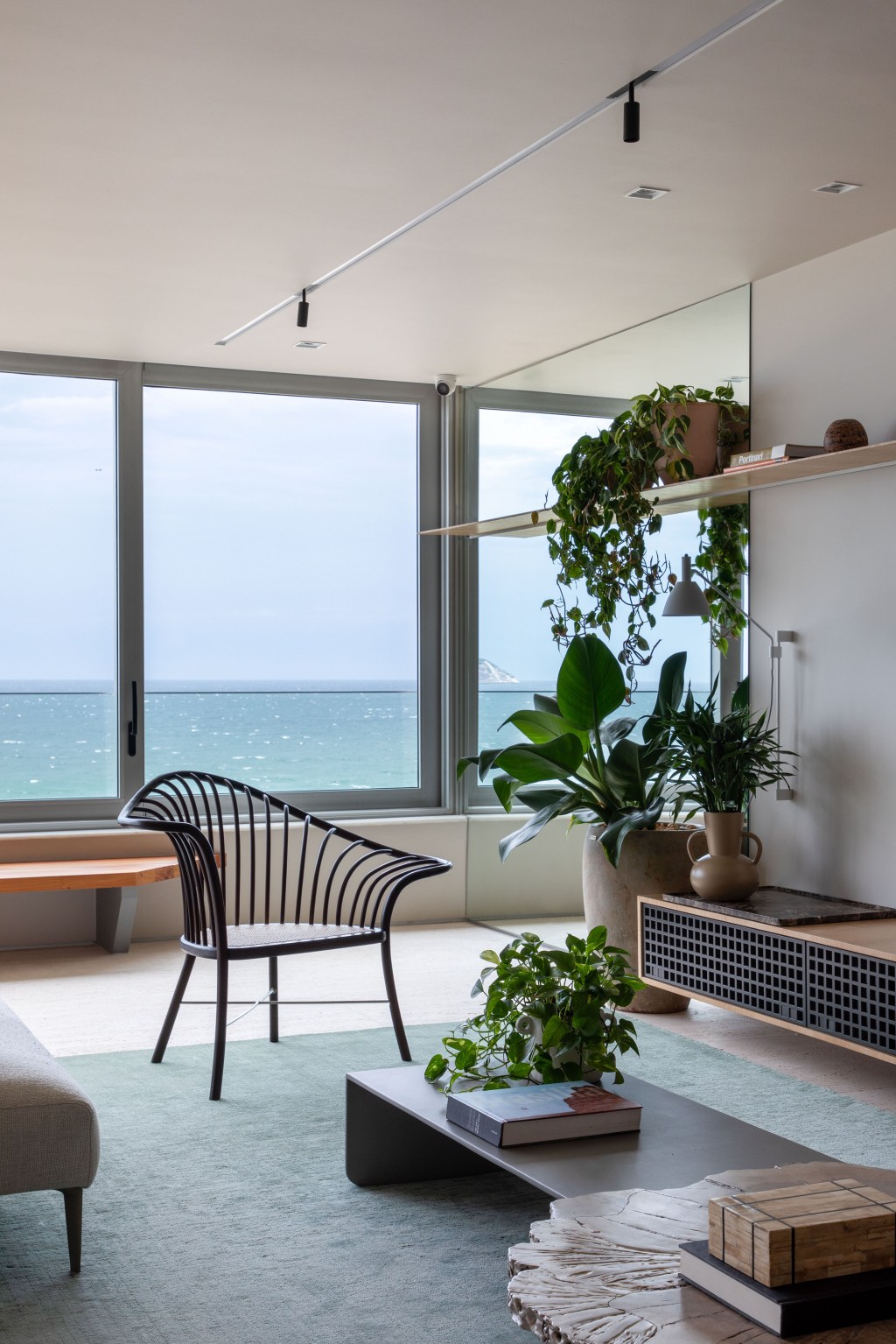 Apartamento com vista para praia ganha espaço de coworking na sala. Projeto de Up3 Arquitetura. Na foto, sala com vista para o mar, aparador e plantas.