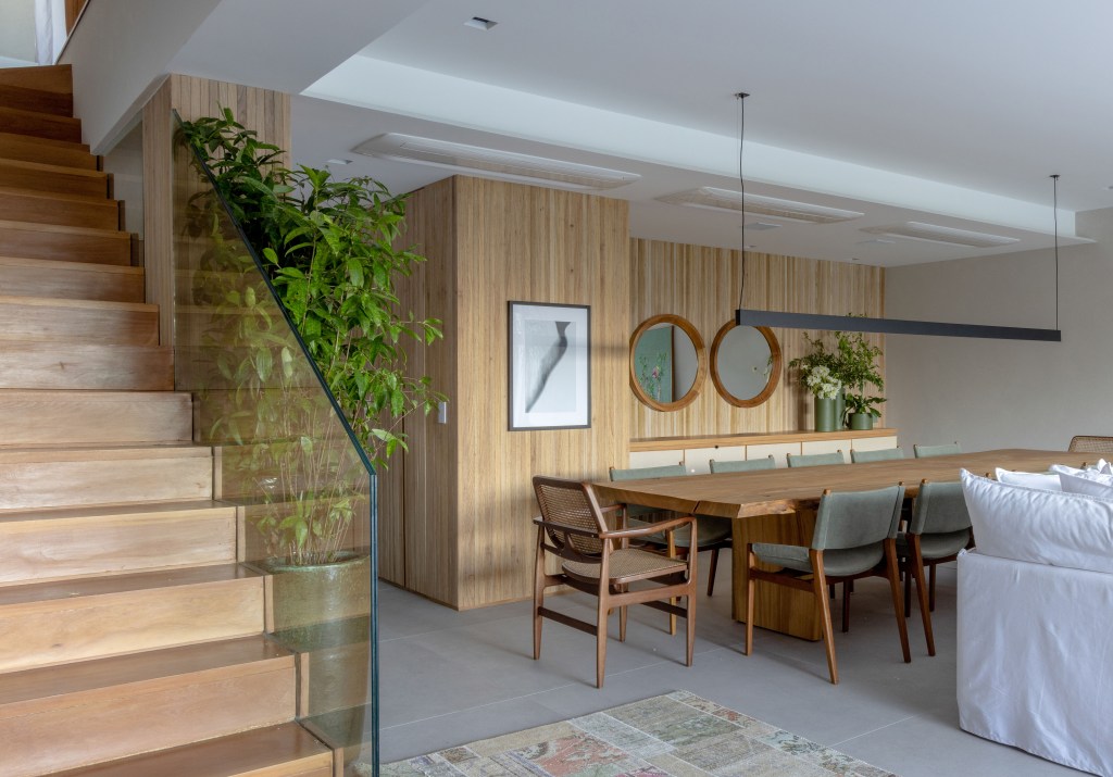 casa-modernizada-projeto-845-m2-cinco-andares-escala-arquitetura-andre-nazareth (1) Casa é modernizada e ganha projeto de 845 m² distribuídos em cinco andares. Projeto Escala Arquitetura. Na foto. sala de jantar com escada e paredes amadeiradas.