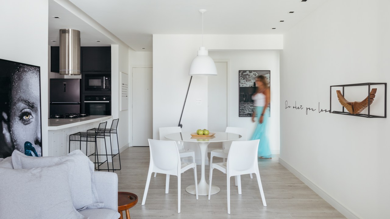 Apê de 84 m² em estilo escandinavo foi pensado para os gatos da moradora. Projeto de Nilton Montarroyos. Na foto. sala de jantar com mesa redonda, quadros e cozinha integrada.