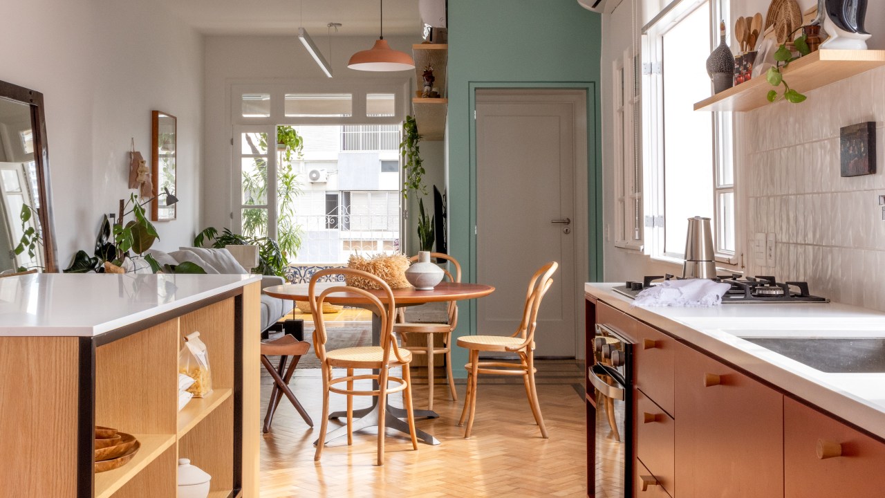 Apê de 90 m² ganha cara de casa com revestimentos charmosos e cores. Projeto Ana Neri. Na foto, cozinha com marcenaria terrosa e sala de jantar com mesa redonda.